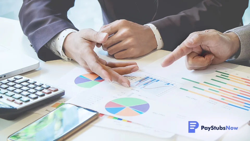 Two business professionals reviewing and discussing employee time tracking charts on a table