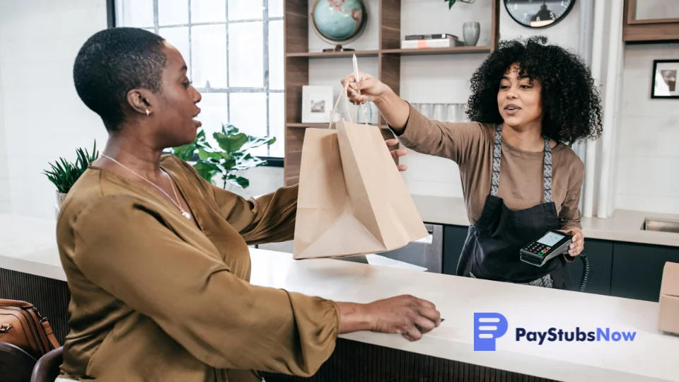 Retail worker handing a paper bag to a customer