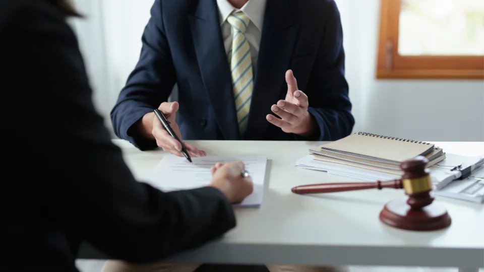 A business owner consults with a lawyer in an office, discussing legal issues related to employee misclassification