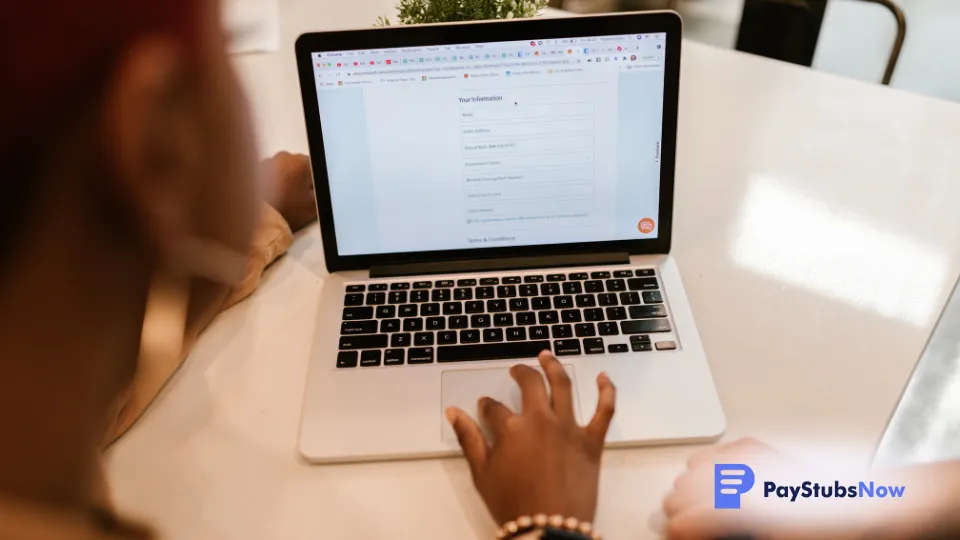 A person sitting at a table with a laptop, working on a grant application