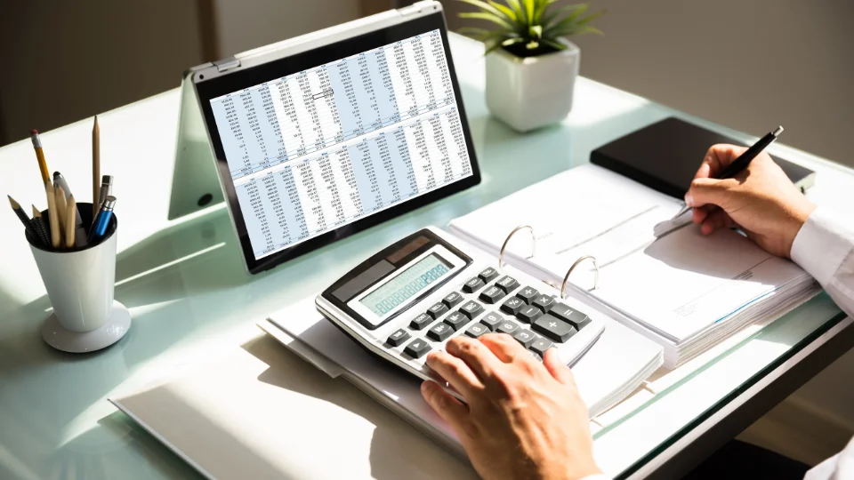 A small business owner uses a calculator and laptop to determine underpayment penalties