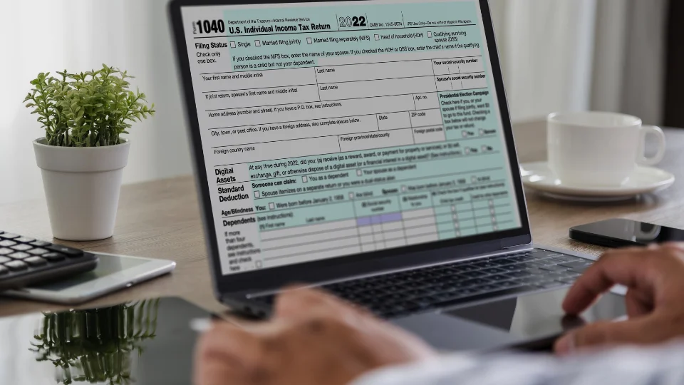 A self-employed person files taxes on a laptop with a tax form open, ensuring timely submission to avoid underpayment penalties