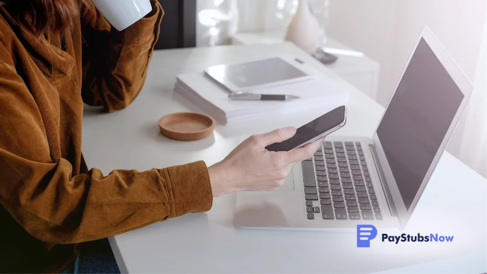 woman at a desk using a laptop and mobile phone